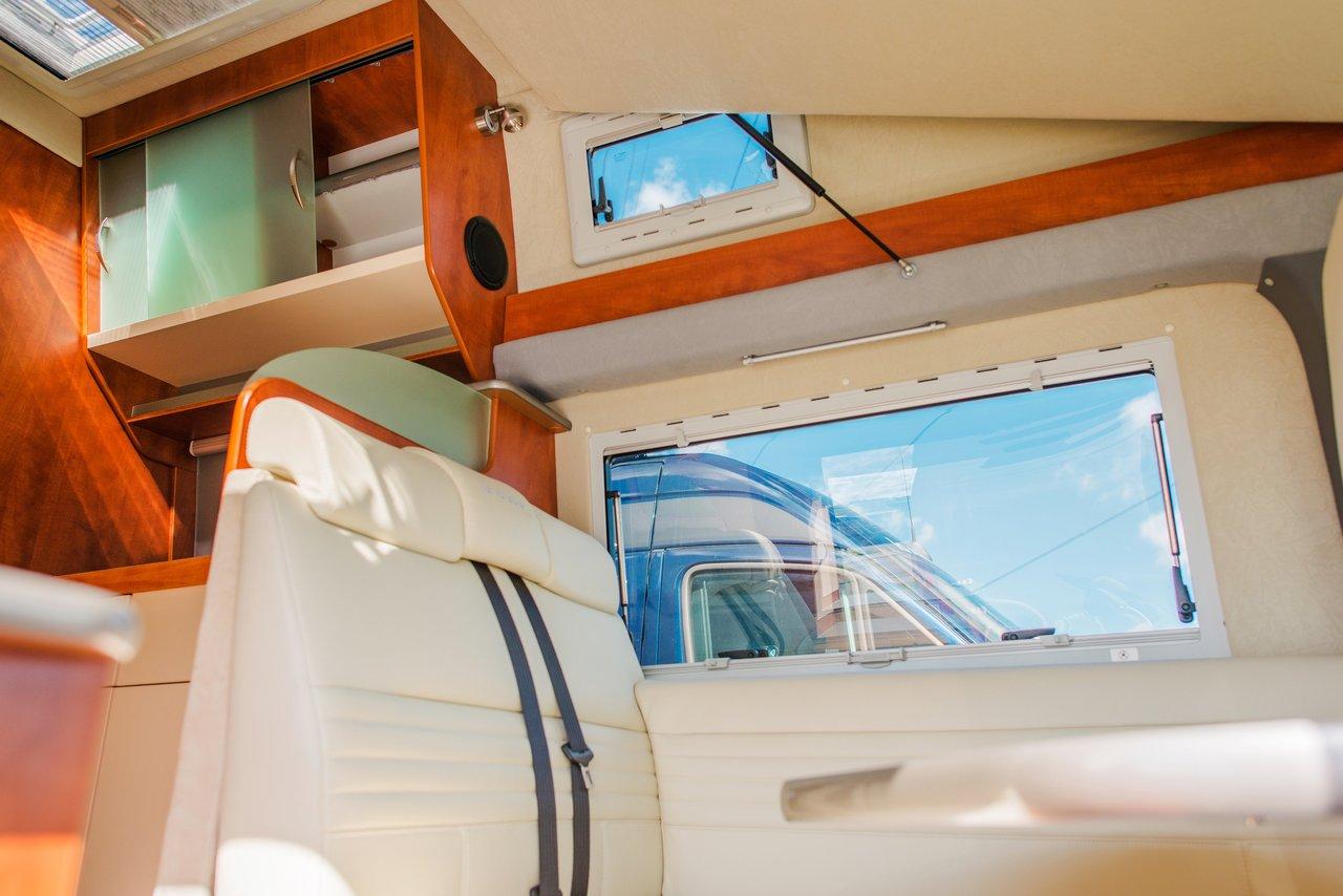 Aperçu de l'agencement intérieur d'un campervan moderne avec lit escamotable, cuisine compacte et panneaux solaires.