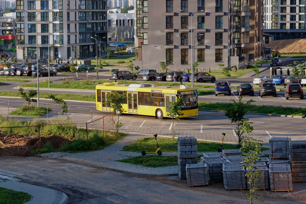 Bus électrique jaune circulant dans une ville moderne avec vélos en libre-service et feux intelligents urbains.