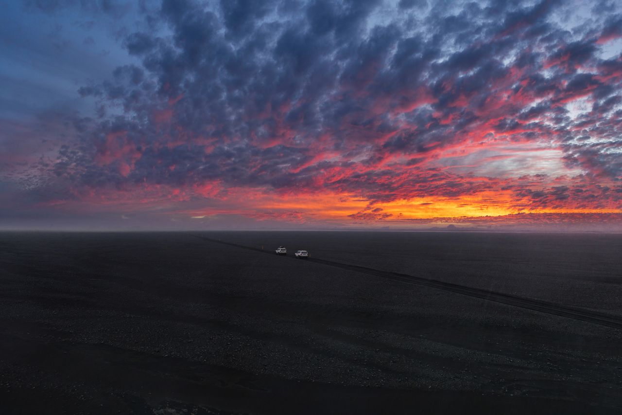 Caravane tout-terrain légère sur piste au bivouac, lumière du soir dorée illuminant la nature sauvage