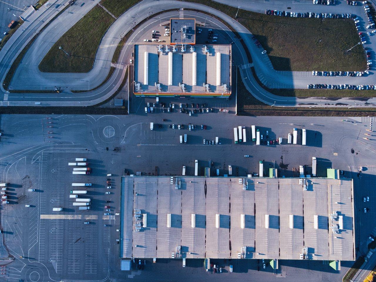 Centre logistique urbain vert avec camions électriques et vélos-cargos en activité dans une zone urbaine dynamique.