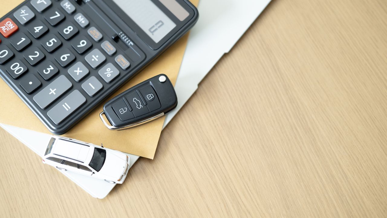 Clé de voiture, pièce détachée, carnet d'assurance et calculatrice pour planification financière et achat automobile sécurisé.