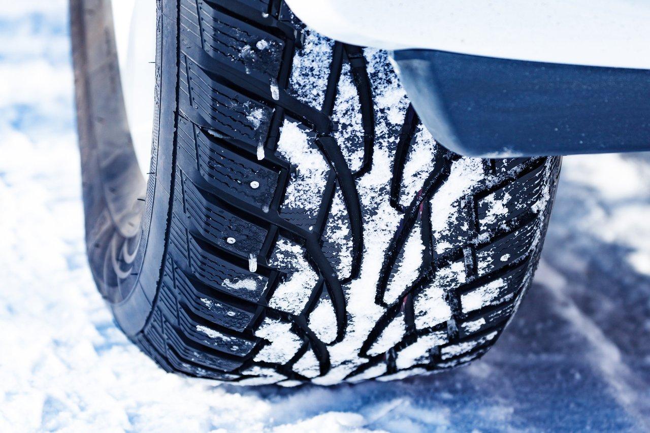 Comparaison des pneus hiver sur neige et glace : étude d'un pneu clouté recouvert de neige.