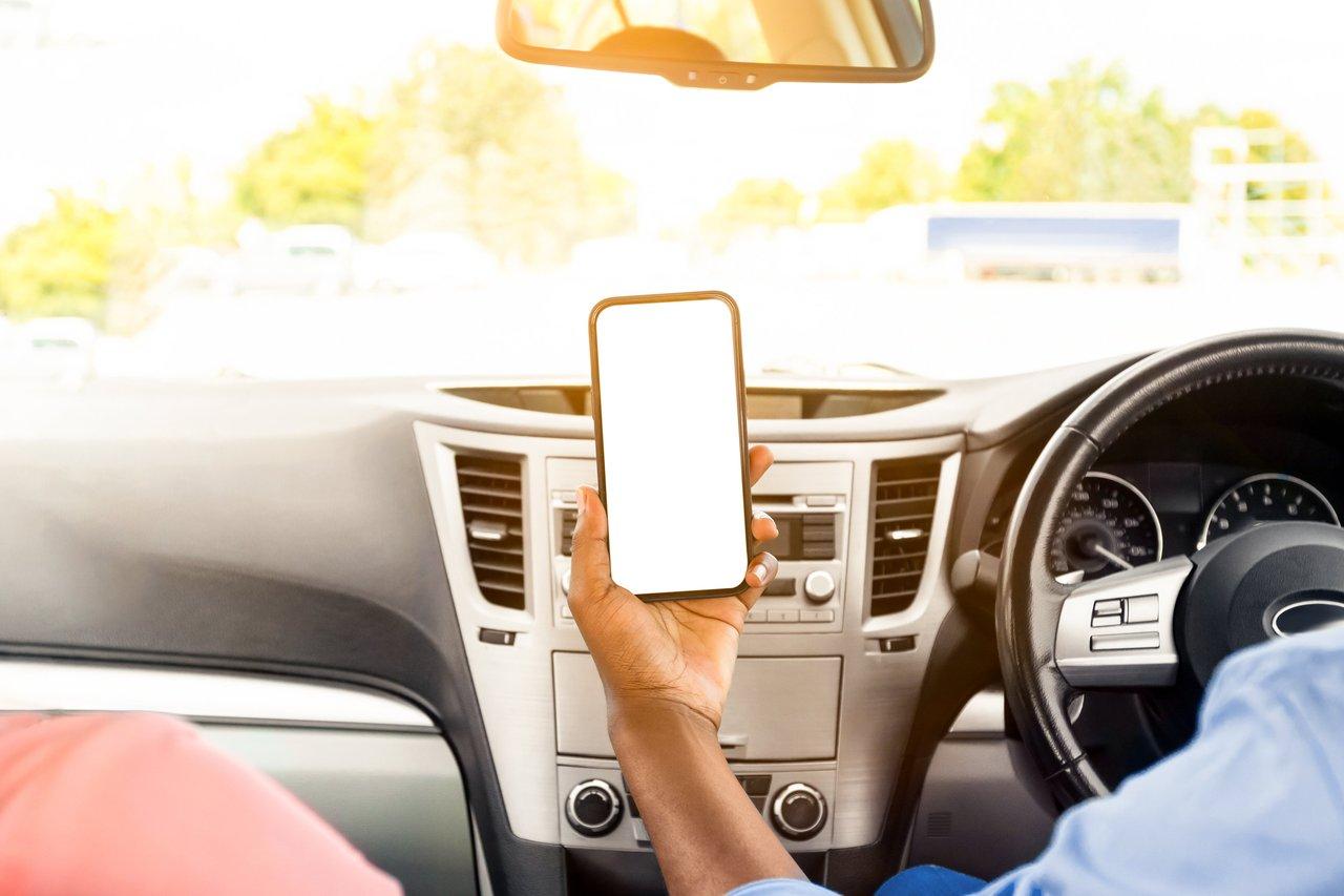 Conducteur utilisant son smartphone pour souscrire une assurance auto temporaire en ligne.