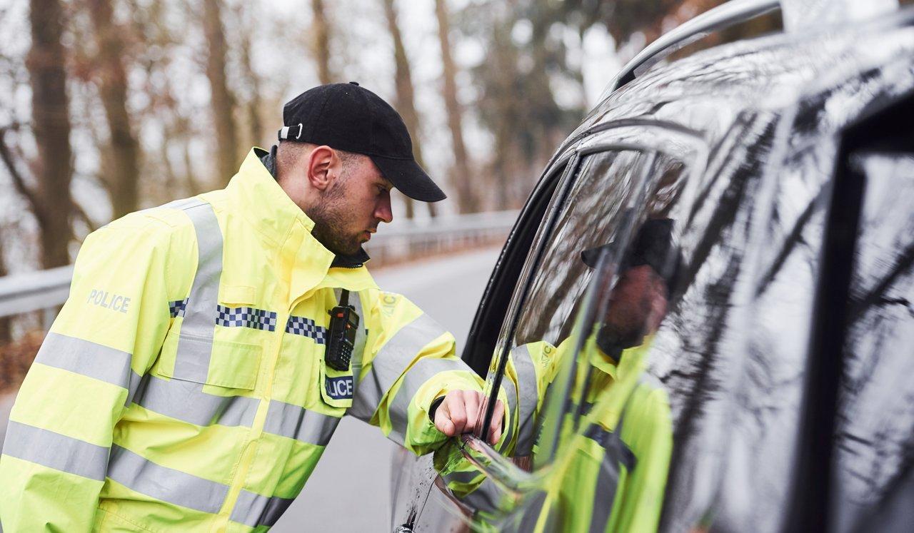 Contrôle de police en Europe : un agent vérifie un véhicule français avec documents d'immatriculation.