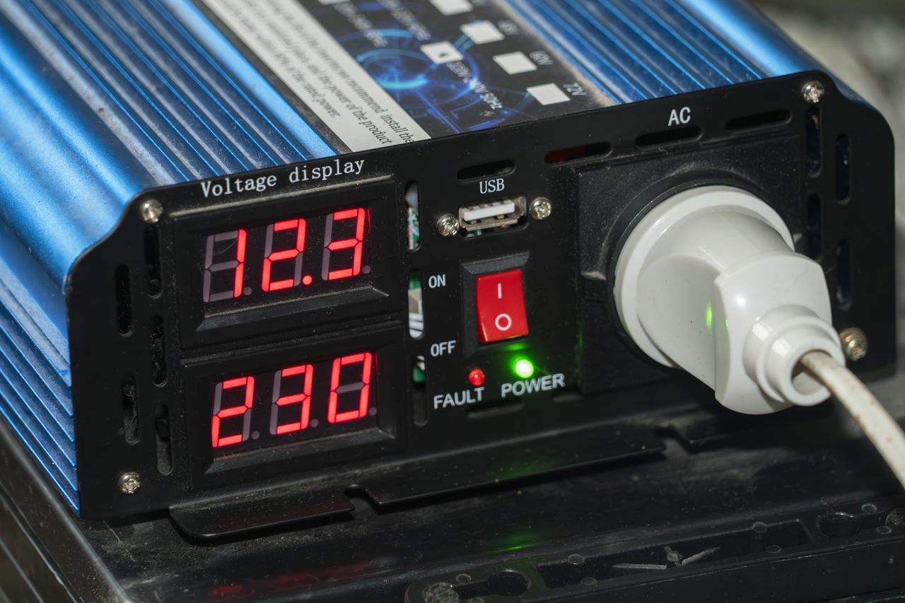 Convertisseur pur sinus 12V‑220V 2000W dans camping‑car, câblage batterie visible et écran LCD affichant puissance, ports USB.