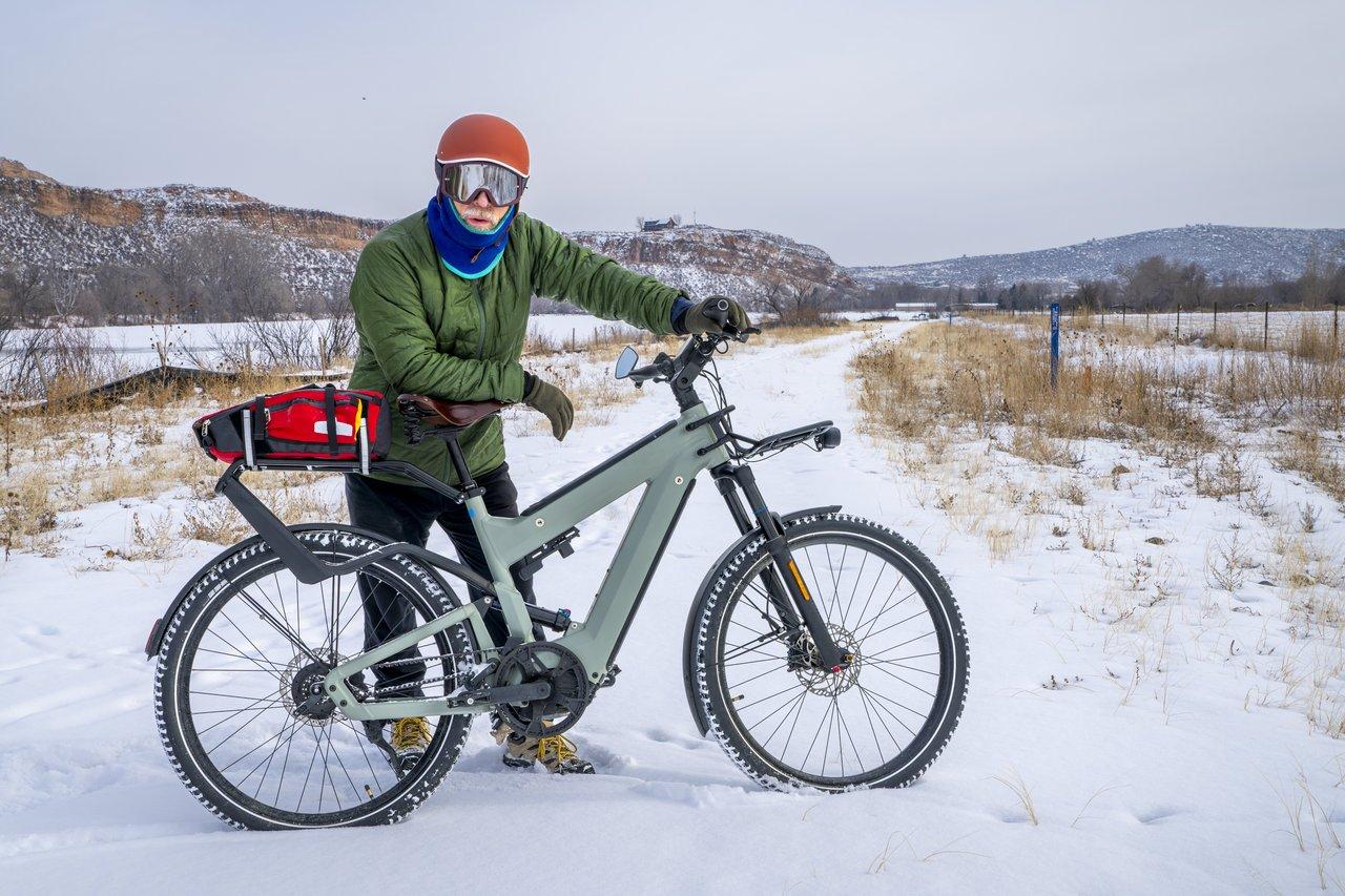 Cycliste en vélo électrique hiver sur piste sécurisée enneigée dans les contreforts du Colorado, pratique de mobilité urbaine.