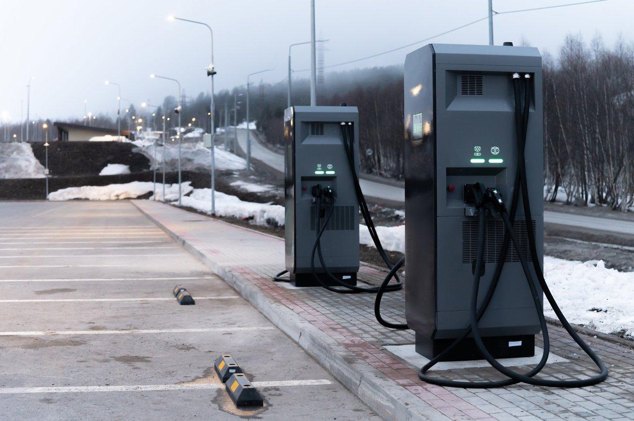 Deux-roues électriques modernes stationnent devant une station de recharge en milieu urbain, symbolisant l'avenir durable des ZFE.
