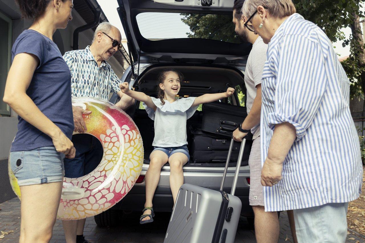 Famille chargant un minivan spacieux sur une autoroute ensoleillée pour un voyage estival 2025.