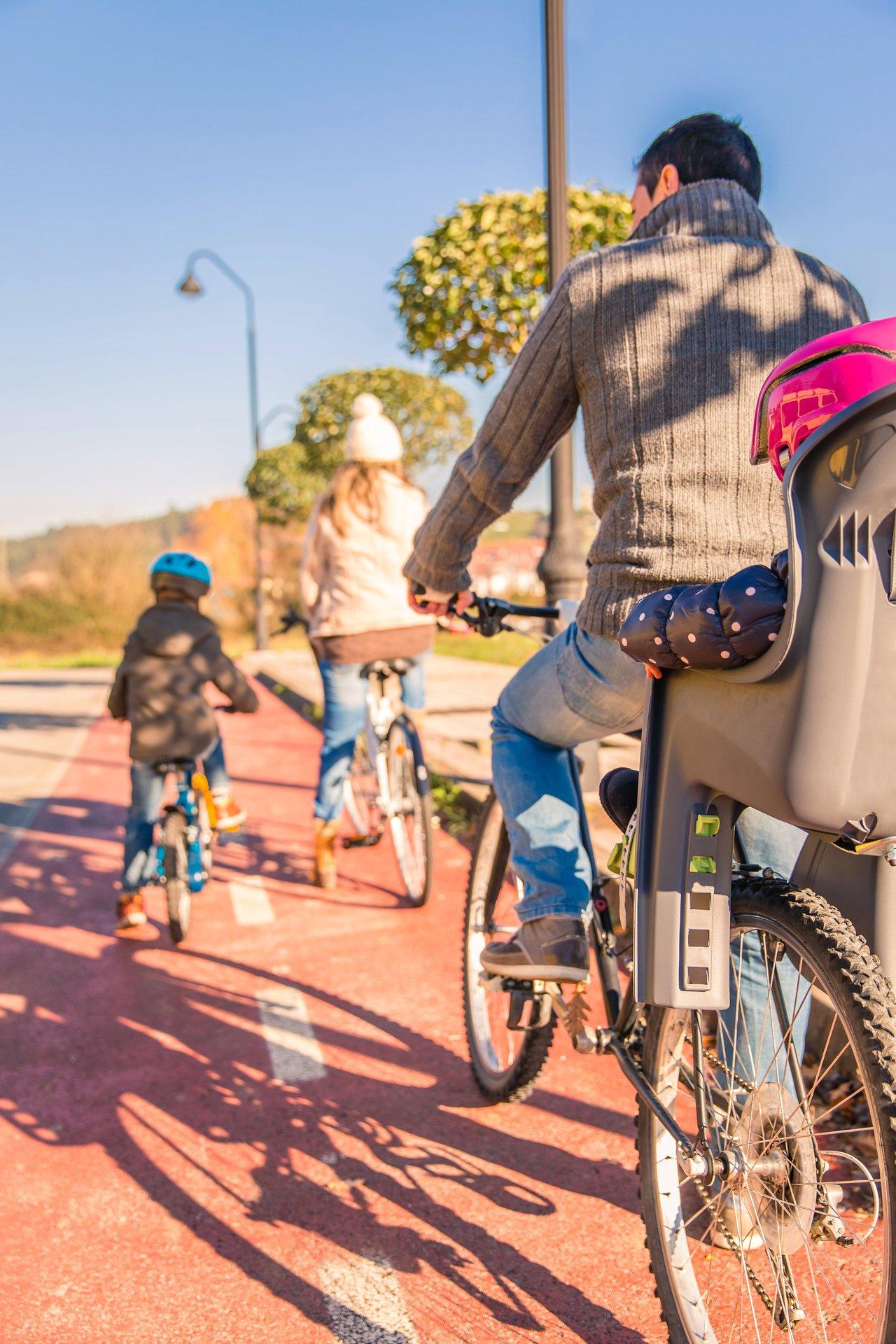Famille urbaine utilisant un family electric cargo bike urban avec enfants équipés de casques pour la rentrée 2025.