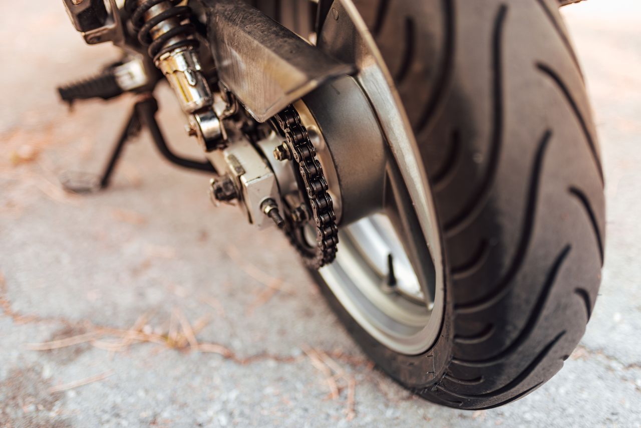 Gros plan pneu moto sportive en appui sur route sèche, bande de roulement visible et adhérence optimale.