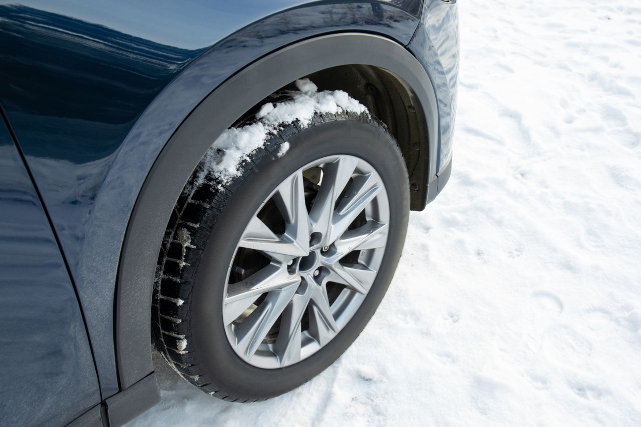 Hyundai Kona Électrique 2026 en hiver, port de charge protégé et pneus neige visibles sur décor enneigé