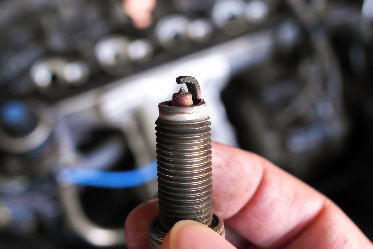 Inspection d'une bougie d'allumage usée pour détecter les signes d'usure et assurer un bon fonctionnement du moteur.