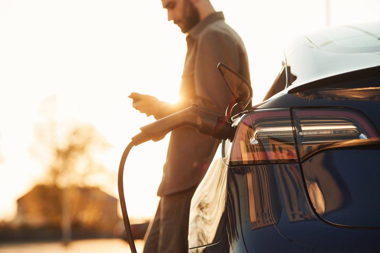 Inspection d'une voiture électrique d’occasion en plein soleil pour détecter d’éventuels défauts de carrosserie.