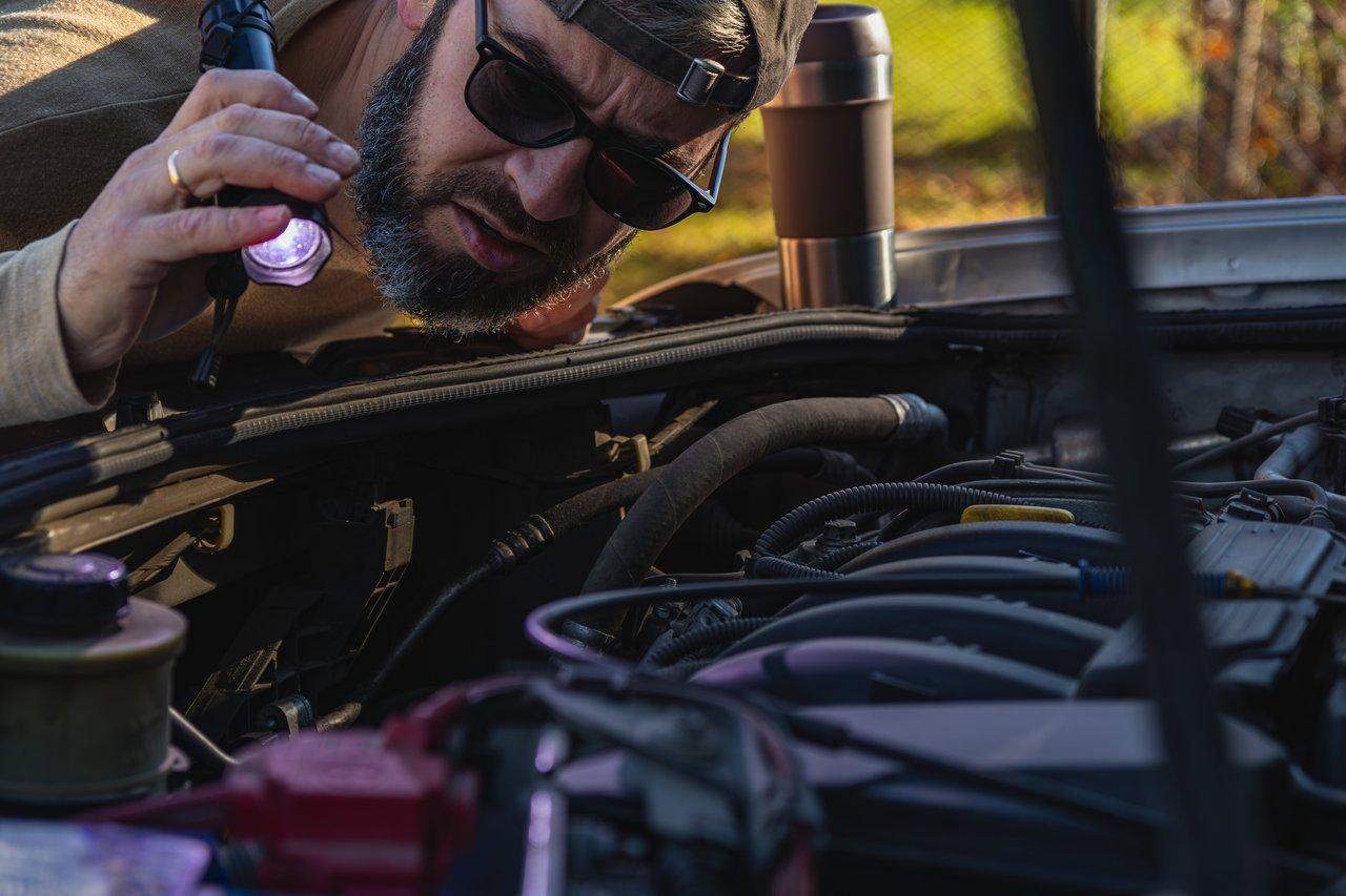 Inspection minutieuse d’un moteur de voiture avec une lampe torche pour détecter une fuite d’huile.