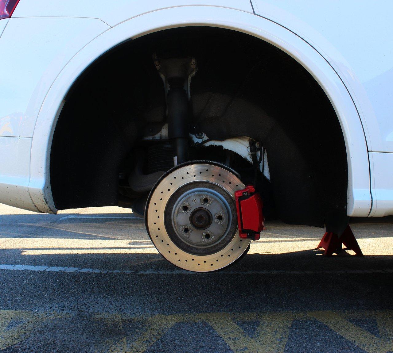 Inspection visuelle des freins d'une voiture pour vérifier les plaquettes et le liquide de frein avant le contrôle technique.