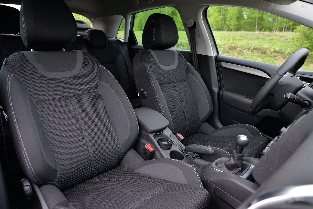 Intérieur d'une voiture compacte avec sièges ergonomiques en tissu noir et tableau de bord moderne.