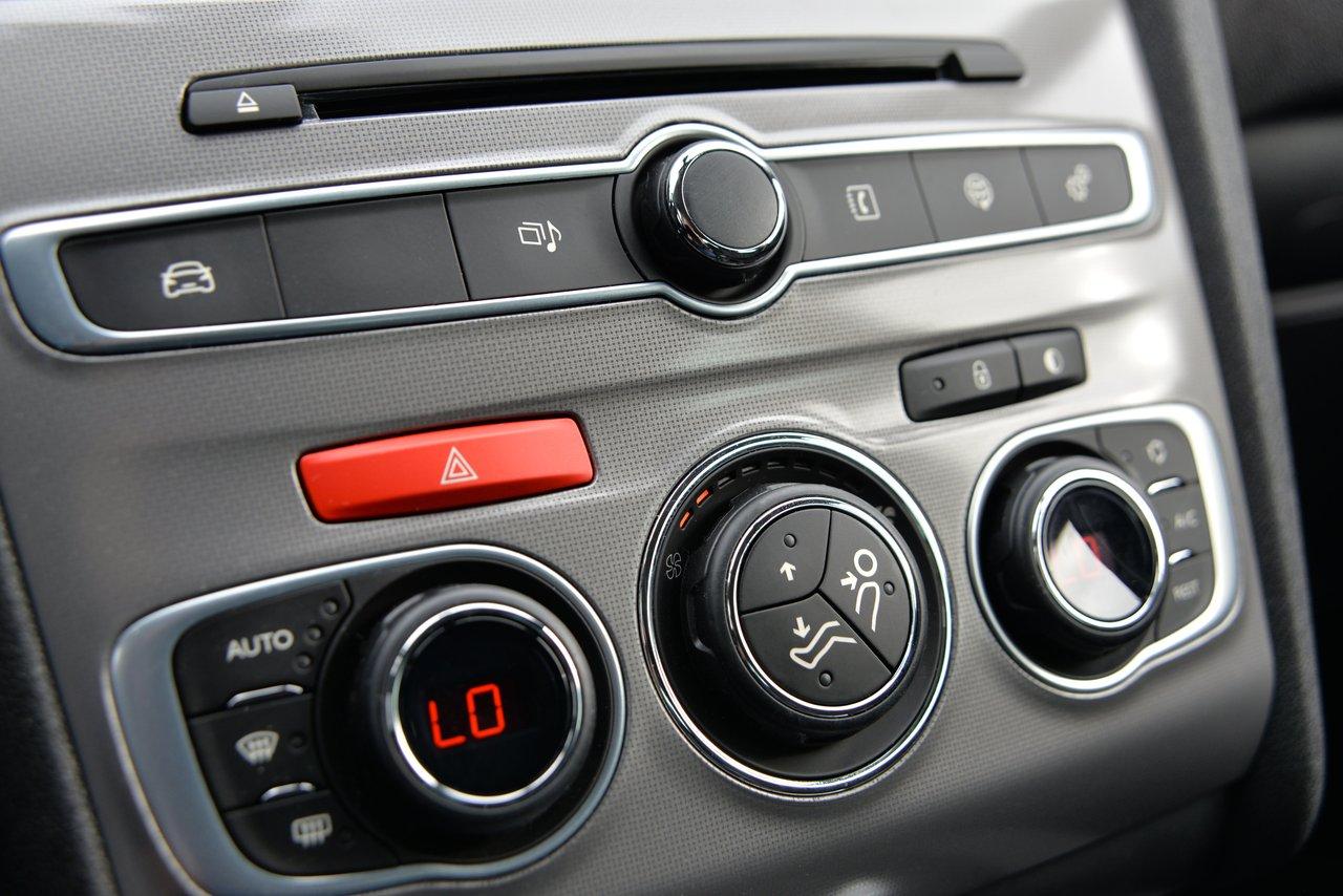 Intérieur épuré d'une voiture moderne avec tableau de bord horizontal, commandes de climatisation et audio.