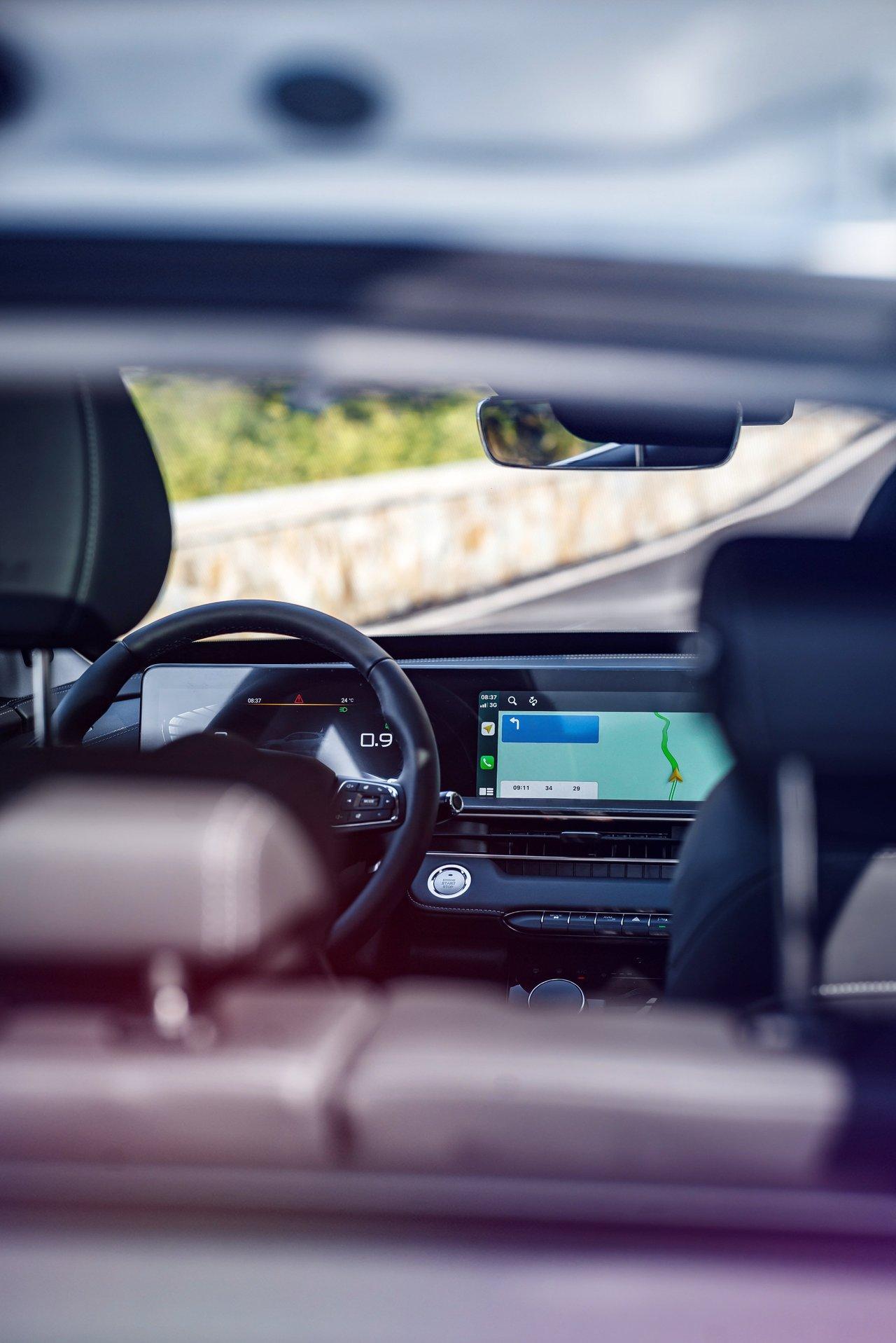 Intérieur moderne d'une électrique coupé sur l'autoroute, avec tableau de bord digital et vue sur la route.