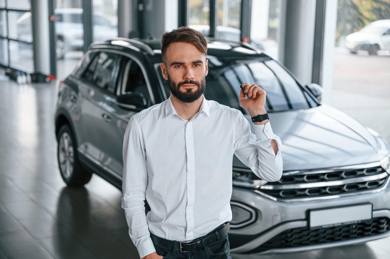 Jeune conducteur choisissant une voiture d'occasion dans un concessionnaire automobile.