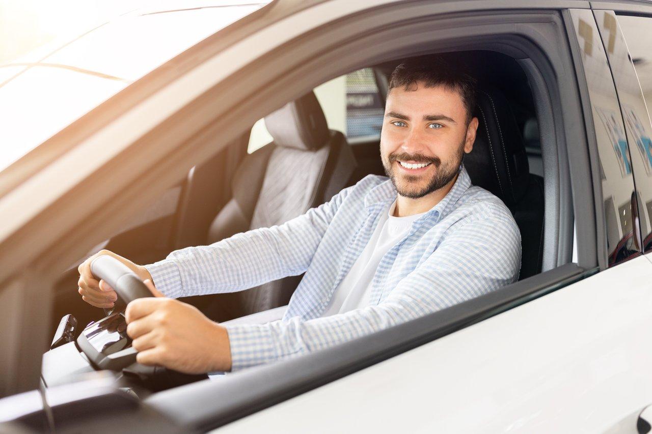 Jeune conducteur lors d'un essai routier avec un expert mécanique pour choisir une voiture adaptée.