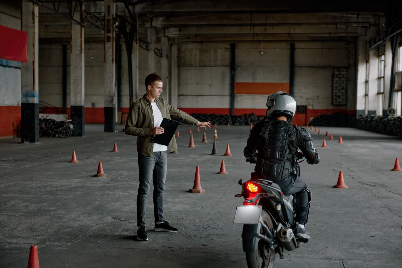 Jeune motard préparant son cours devant une moto-école, casque et équipement complet pour sécurité routière.