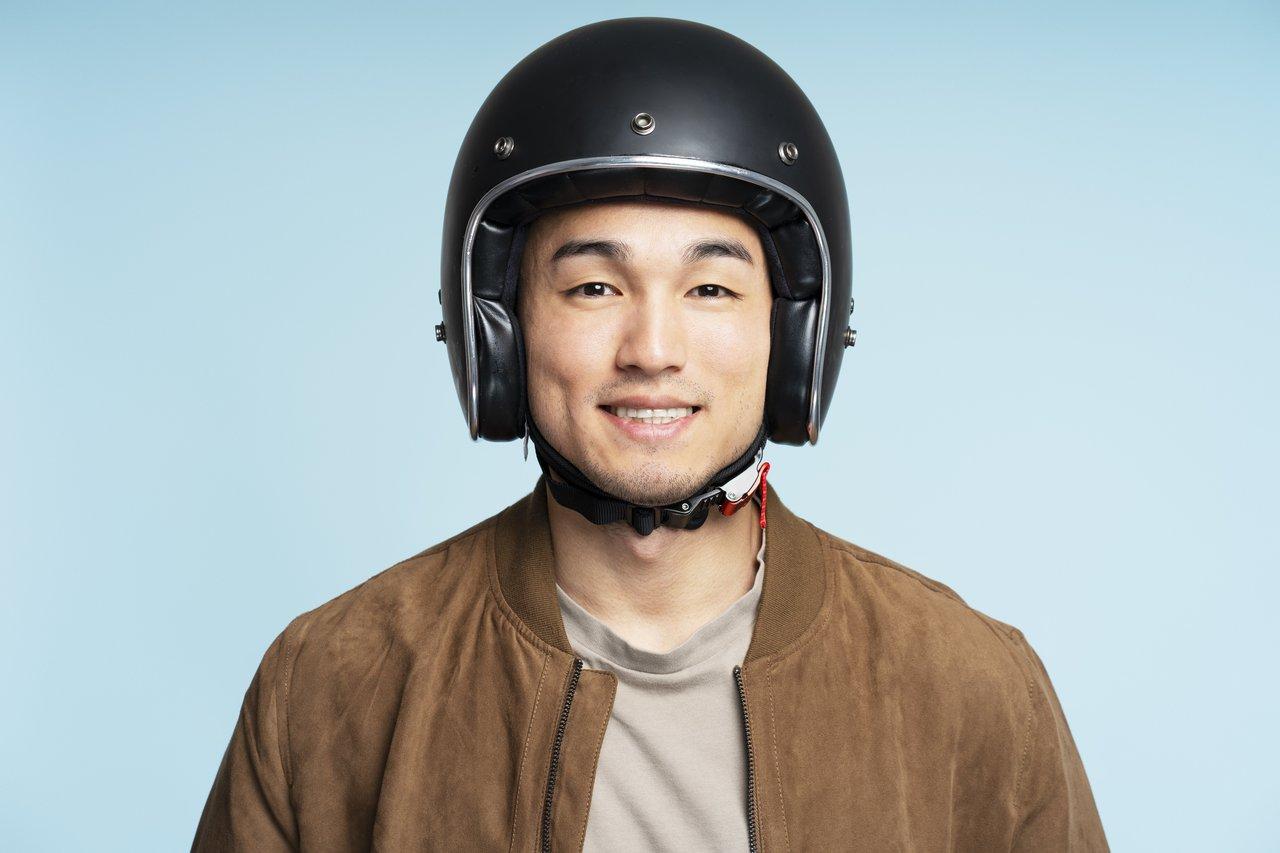 Jeune motard souriant portant un casque connecté avec caméra embarquée pour une sécurité optimale.
