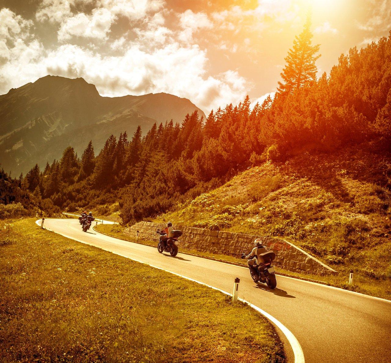 Motard admirant la vue panoramique alpine lors d’un road-trip en deux-roues à couper le souffle.