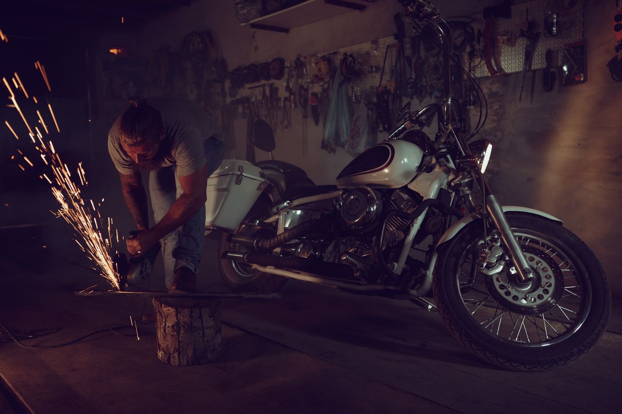 Moto rétrofitée électrique en atelier, technicien installant batterie et moteur sur cadre classique