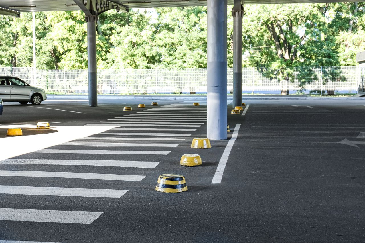 Passage piéton urbain dégagé avec marquage au sol, véhicule garé en arrière-plan et piéton traversant.