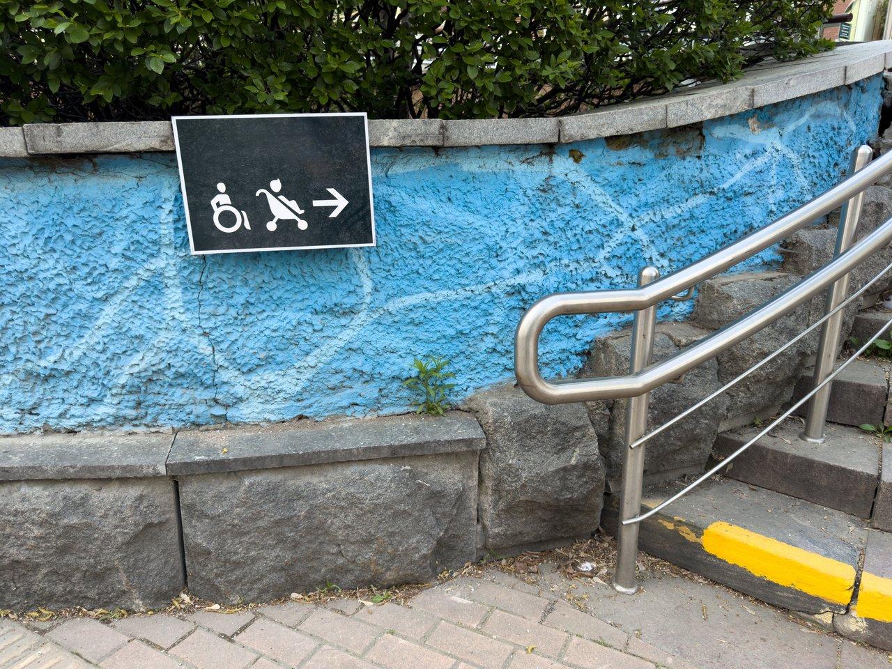 Personne en fauteuil roulant utilisant une application de navigation urbaine avec balises audio dans une station de métro accessible.