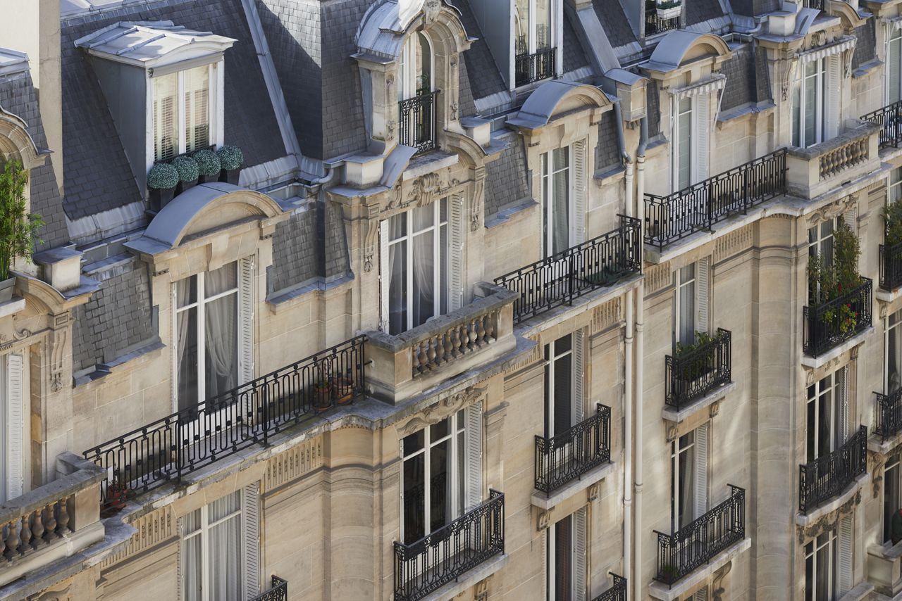 Rangée de sept citadines compactes garées en ville, vue trois quarts avant, quartier urbain parisien.