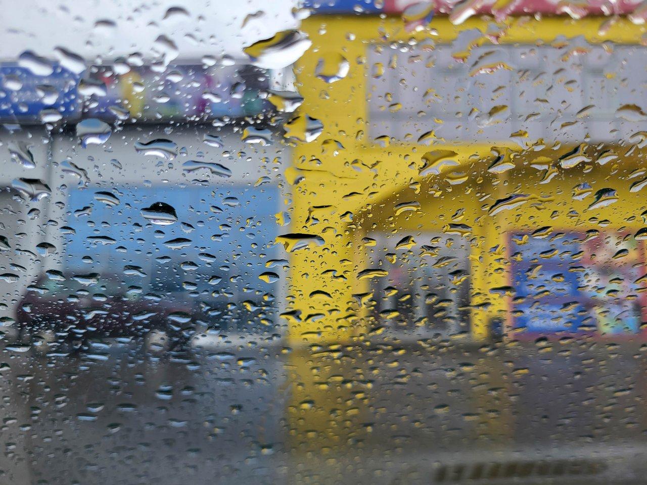 Scooter three-wheeler Piaggio MP3 en pluie, illustrant sa stabilité et sécurité en conditions humides en ville.