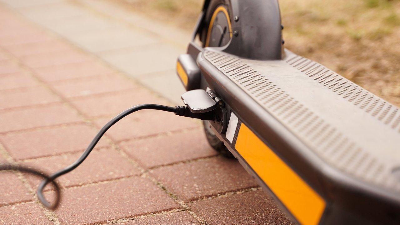 Station de recharge pour scooter électrique en milieu urbain, illustrant la facilité de charge et la mobilité électrique.