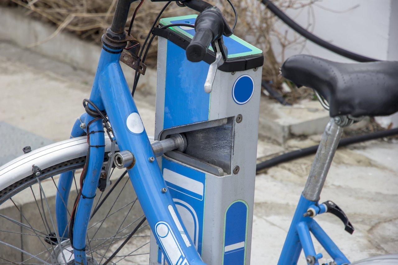 Station de vélos en libre-service moderne sur une piste cyclable urbaine ensoleillée, idéale pour des trajets quotidiens en ville.