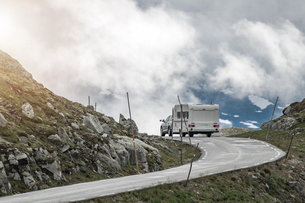 SUV towing caravan countryside sur une route de campagne alpine, attelage solide pour une conduite sécurisée.