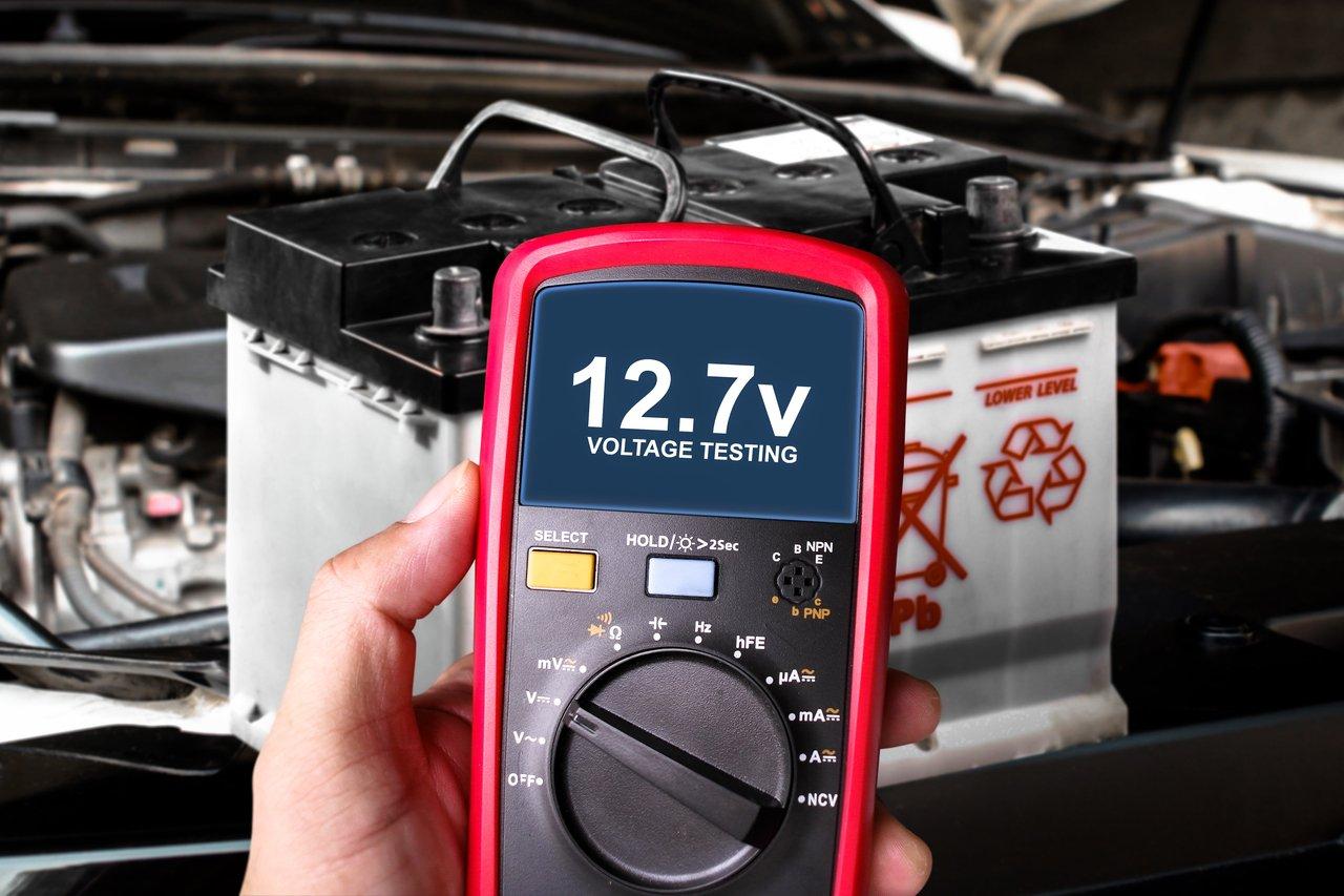 Test de tension d'une batterie automobile avec un multimètre numérique pour diagnostiquer une panne de démarrage.