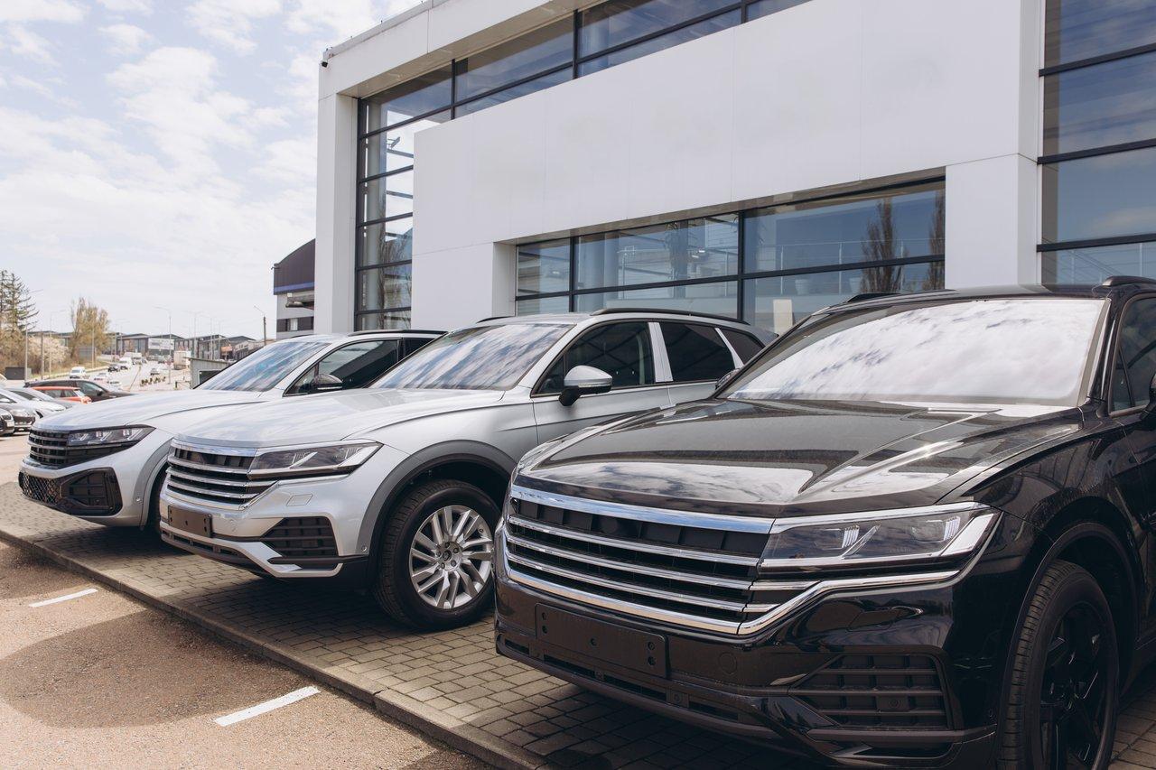 Trois plug-in hybrid SUVs alignés devant un concessionnaire, illustrant leurs différentes tailles et designs.