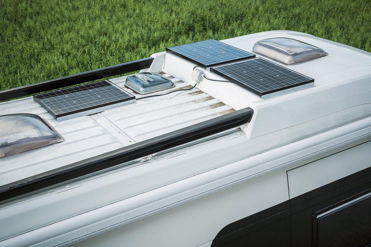 Un camper électrique en recharge solaire sur le toit dans un camping écologique, favorisant un tourisme durable.
