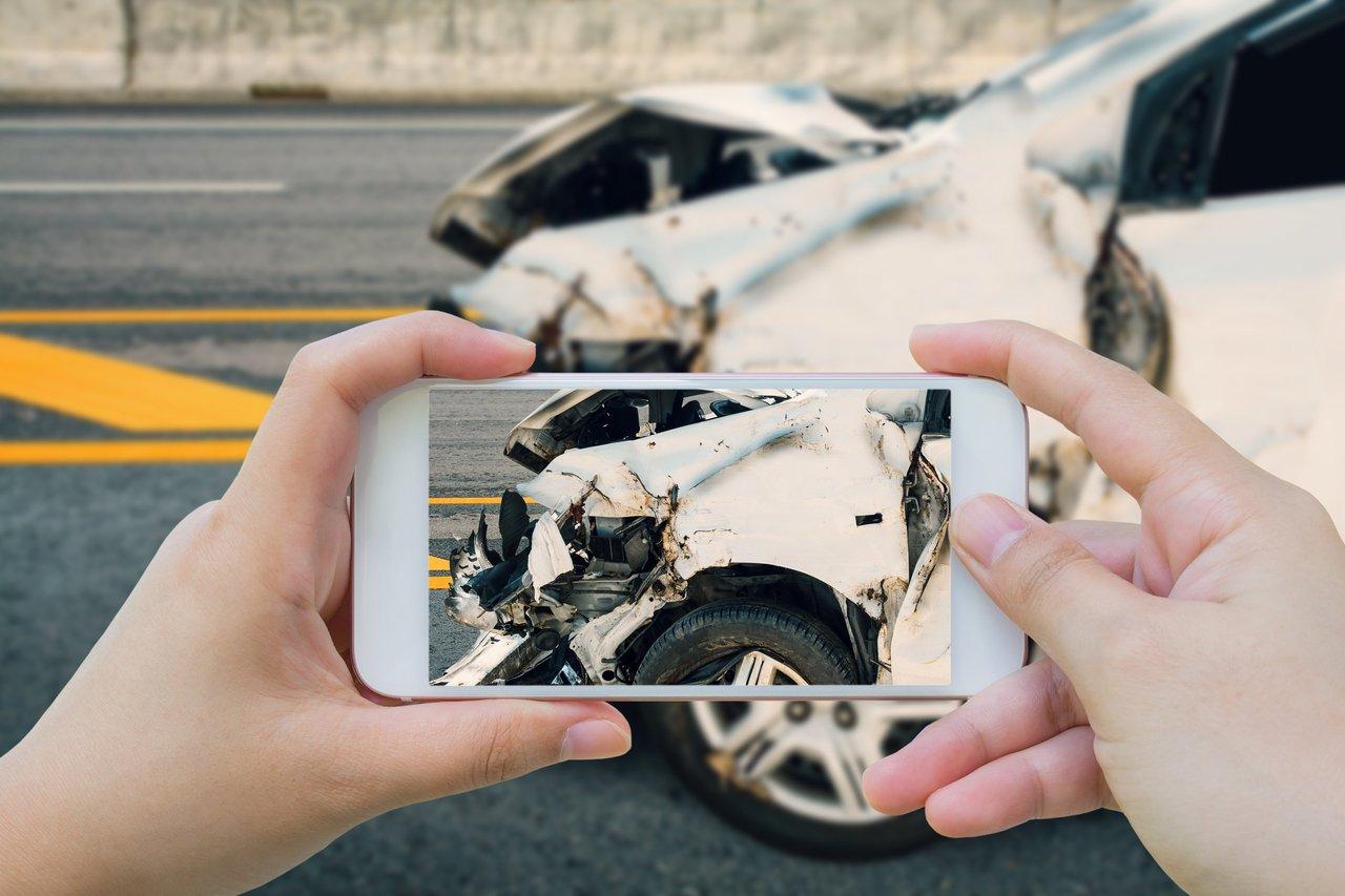 Un conducteur prenant des photos de l’accident pour documenter les dommages en l’absence de constat amiable.