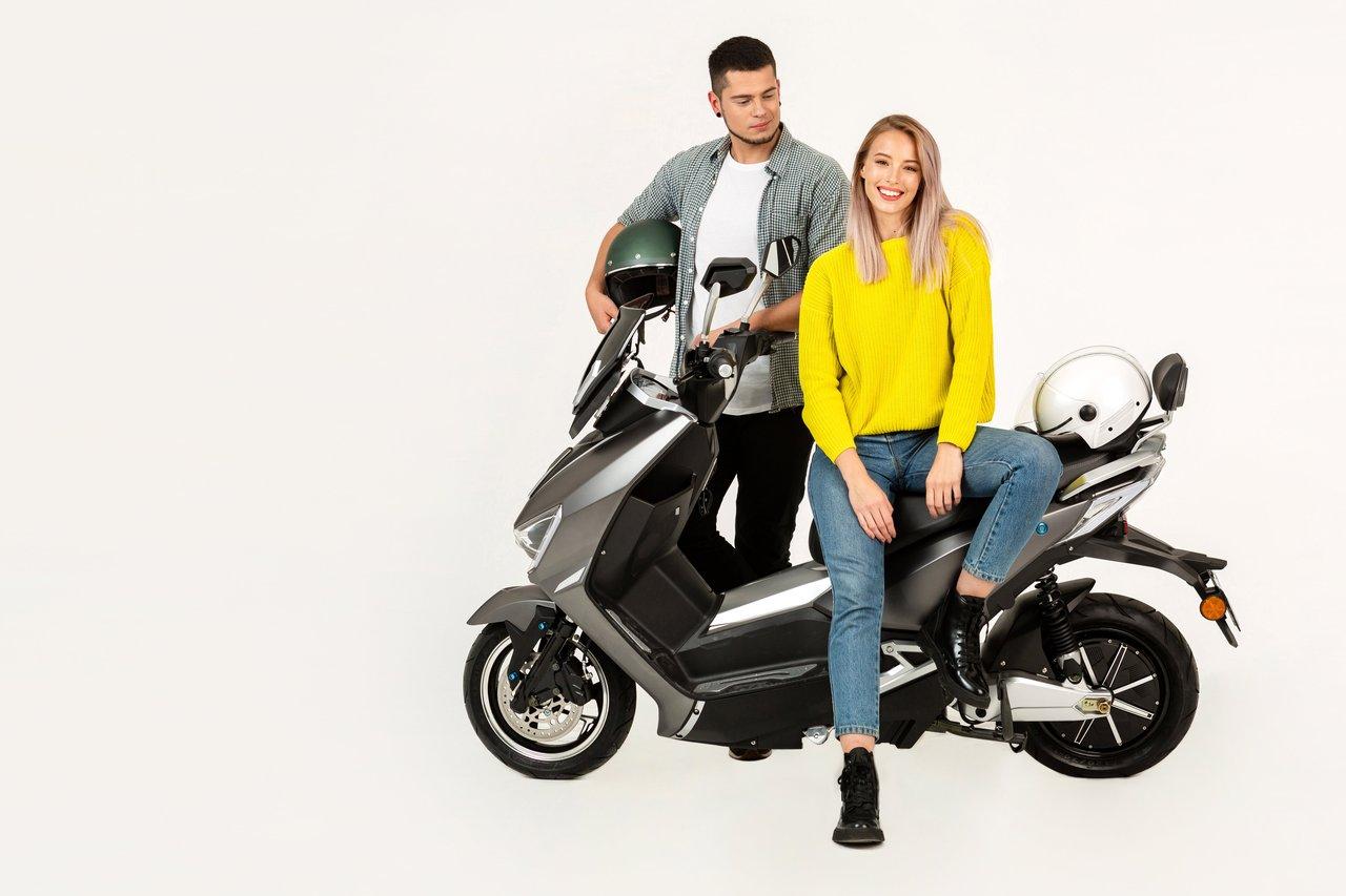 Un couple souriant profite d’un electric scooter vs motorcycle city pour une balade urbaine écologique et fun.