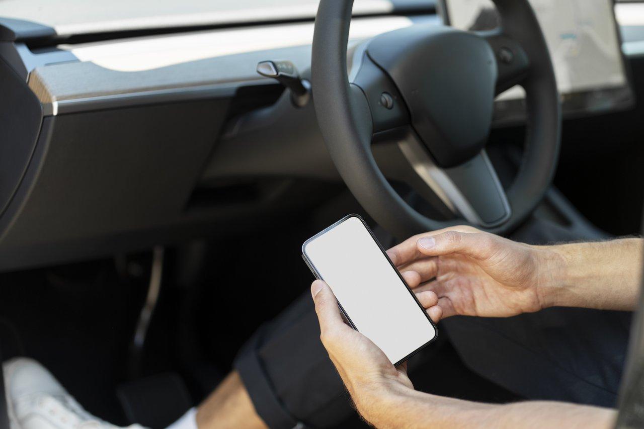 Un homme utilisant un adaptateur OBD2 connecté à son smartphone pour effectuer un diagnostic complet de sa voiture.
