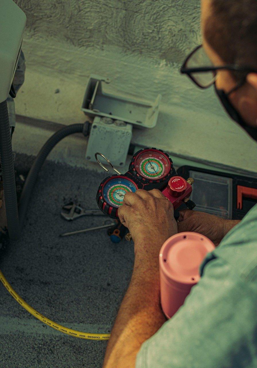 Un technicien en maintenance d'air conditionné vérifie l’unité extérieure pour assurer un bon fonctionnement à la rentrée.