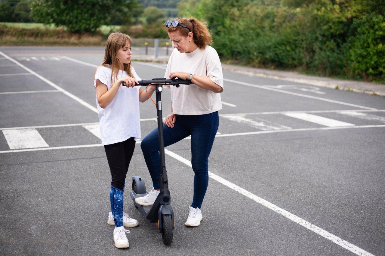 Une famille préparant une balade en trottinette électrique sur piste cyclable urbaine, équipée pour la sécurité.