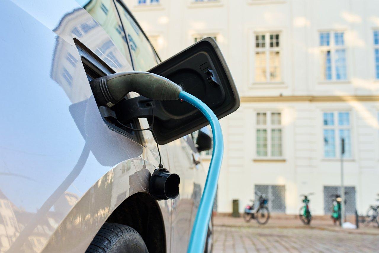 Une voiture électrique en cours de recharge dans un environnement urbain, symbole de mobilité durable et zéro émission.