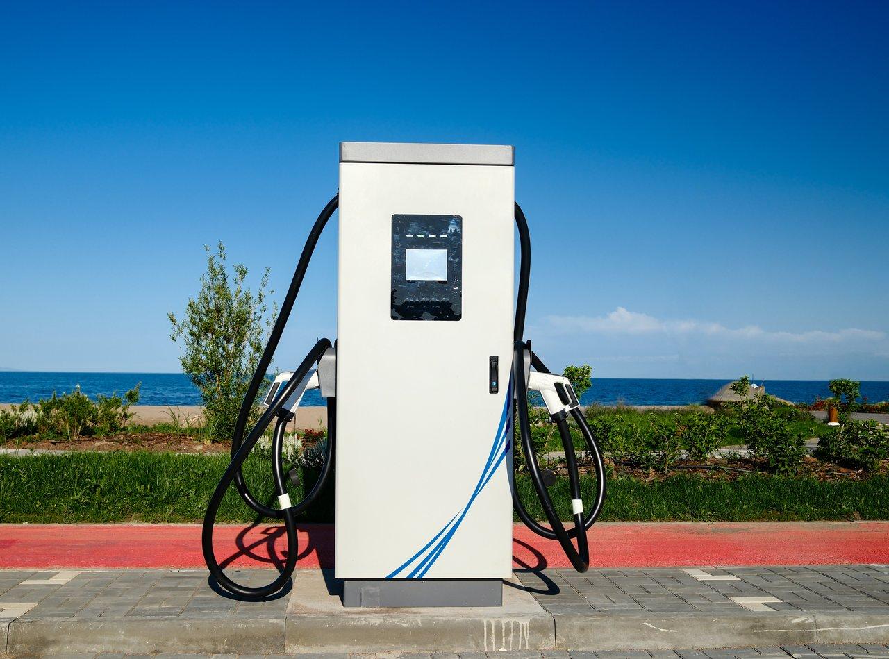 Véhicule électrique en recharge rapide sur autoroute, paysage rural en arrière-plan, illustration de la mobilité durable.