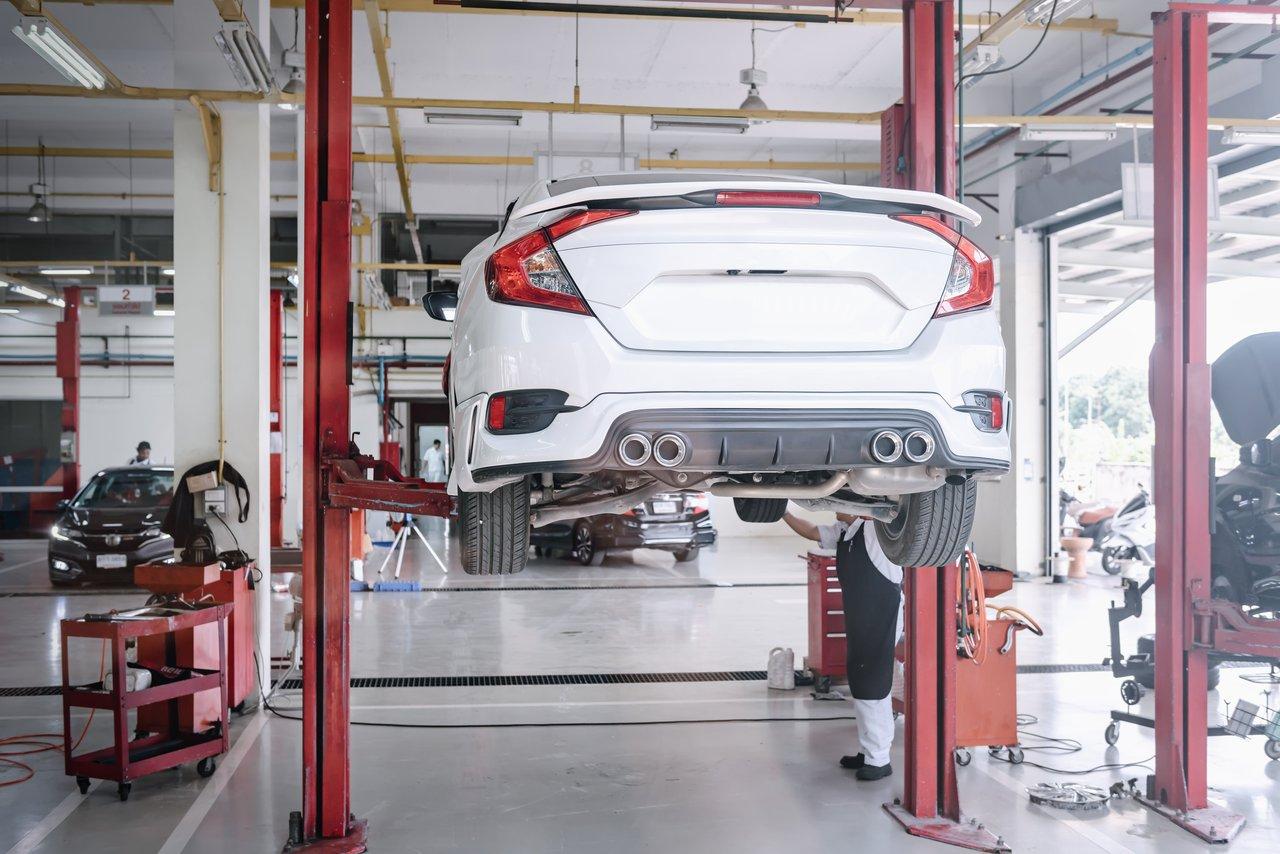 Véhicule en cours de maintenance dans un garage, avec contrôle des pneus et moteur propre, pour optimiser la consommation.