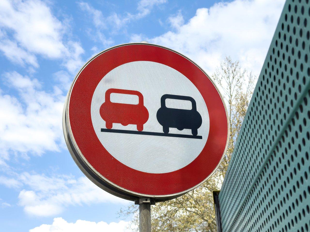 Véhicule tractant une caravane avec panneaux de limitation de vitesse et signalisation de dépassement interdit.