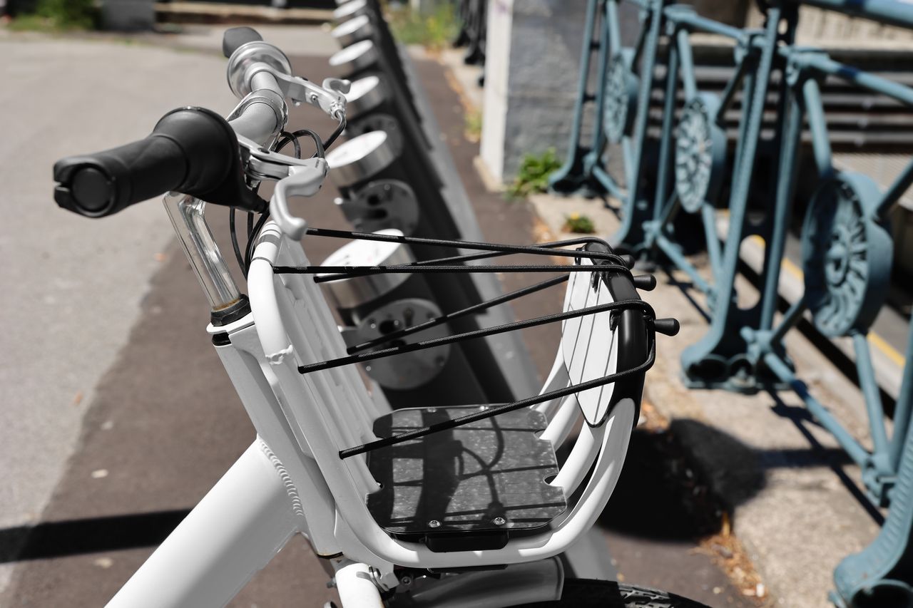Vélo électrique chargé sur porte-vélo d'attelage, plaque et feux visibles, transport sécurisé en ville.