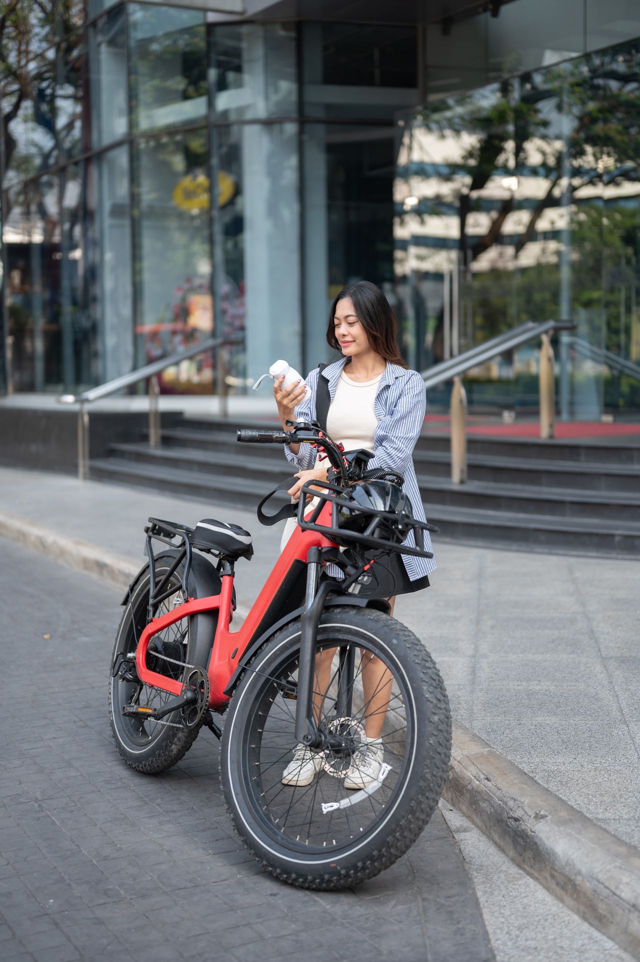 Vélo électrique urbain moderne à cadre ouvert avec panier avant et batterie amovible, stationné en centre-ville.