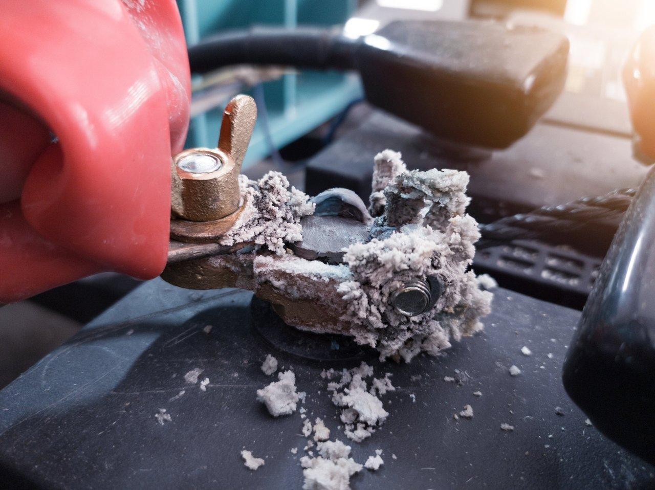 Vérification de la sécurité de la batterie automobile dans un compartiment moteur propre, en évitant tout contact avec la poudre de fungus.